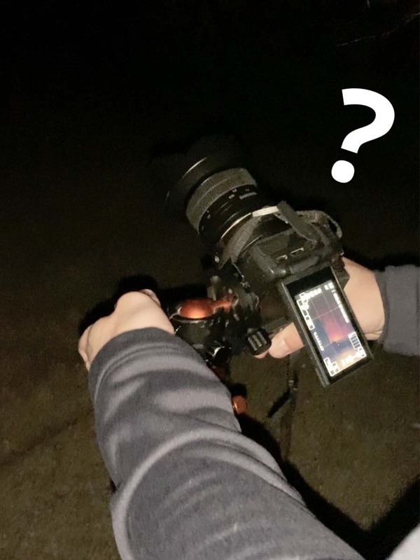 A photographer checking the histogram on the back of their camera in the dark